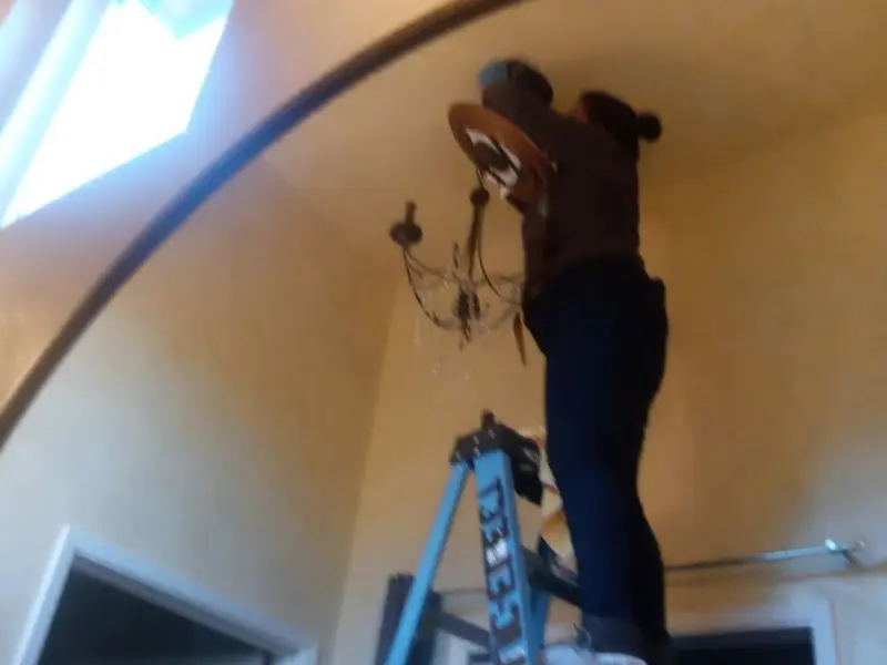 Electrician installing a chandelier in a West Point residence